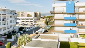 Una zona residencial costera con edificios modernos, un puerto deportivo y coches aparcados.