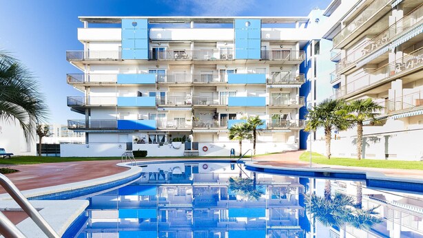 Un hotel de varios pisos con piscina, balcones y palmeras.