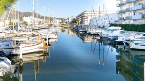 Un puerto deportivo con barcos amarrados a lo largo del agua, rodeado de edificios y vegetación.