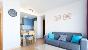 Una sala de estar moderna con un sofá gris, una mesa de centro de madera y un comedor con una mesa y sillas azules.