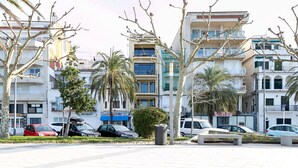 Eine moderne Stadtstraße mit mehrstöckigen Gebäuden, parkenden Autos und Palmen.