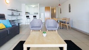 Ein modernes Wohnzimmer mit einer Couch, zwei Sesseln, einem Couchtisch und einem Essbereich mit Tisch und Stühlen.
