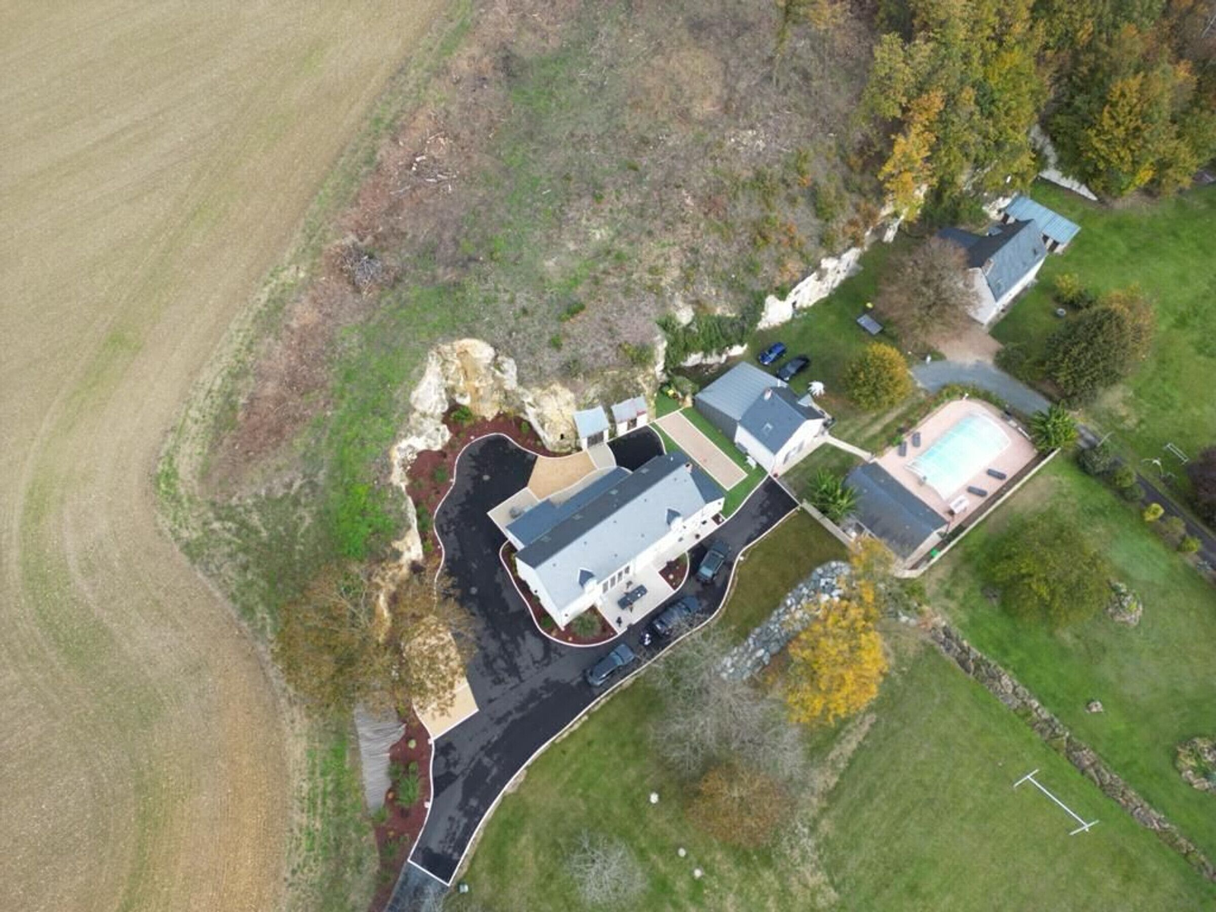 An aerial view of a residential area with multiple houses, a swimming pool, and a well-maintained lawn.