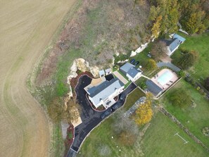 An aerial view of a residential area with multiple houses, a swimming pool, and a large open field.