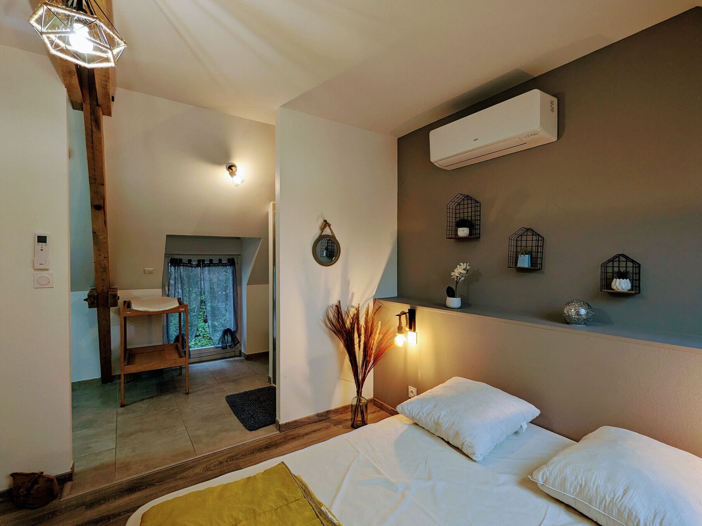 Une chambre à coucher comprenant un lit, des lampes de chevet, un appareil de climatisation et des étagères décoratives murales.