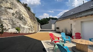 A building with a sloped roof, a paved driveway, and outdoor seating with chairs and a table.