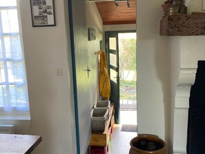 Enter a charming hallway with a door leading to a serene outdoor space and a glimpse of a lush garden.