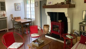 Ein gemütliches Wohnzimmer mit Kamin, Holzmöbeln und einem Essbereich mit Stühlen und einem Tisch.