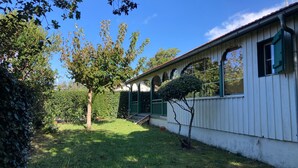 Ein weißes Gebäude mit einer grünen Veranda und einem kleinen Baum davor.