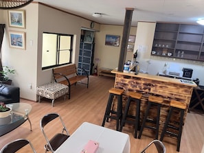 A cozy room with a wooden bench, a small table with a patterned tablecloth, and a bar area with stools.