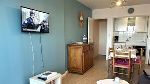 Ein Wohnzimmer mit Fernseher, Holzschrank und einem kleinen Tisch mit Tassen.