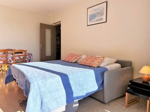 Um quarto com uma cama, uma cadeira, uma mesa e uma luminária.