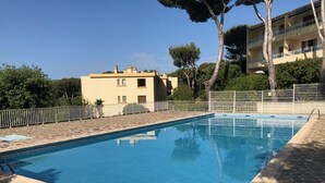 A rectangular swimming pool with stone tiles, surrounded by a low stone wall and a metal fence. - 2-room apartment, 4 guests, quiet in Bormes-les-Mimosas (Bormes-les-Mimosas)