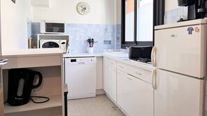 A compact kitchen with white cabinets, a microwave, a dishwasher, and a refrigerator. - 2-room apartment, 4 guests, quiet in Bormes-les-Mimosas (Bormes-les-Mimosas)