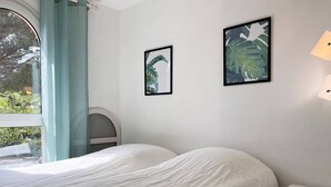 Ein Schlafzimmer mit einem Bett, einem Nachttisch und zwei gerahmten Bildern an der Wand.
