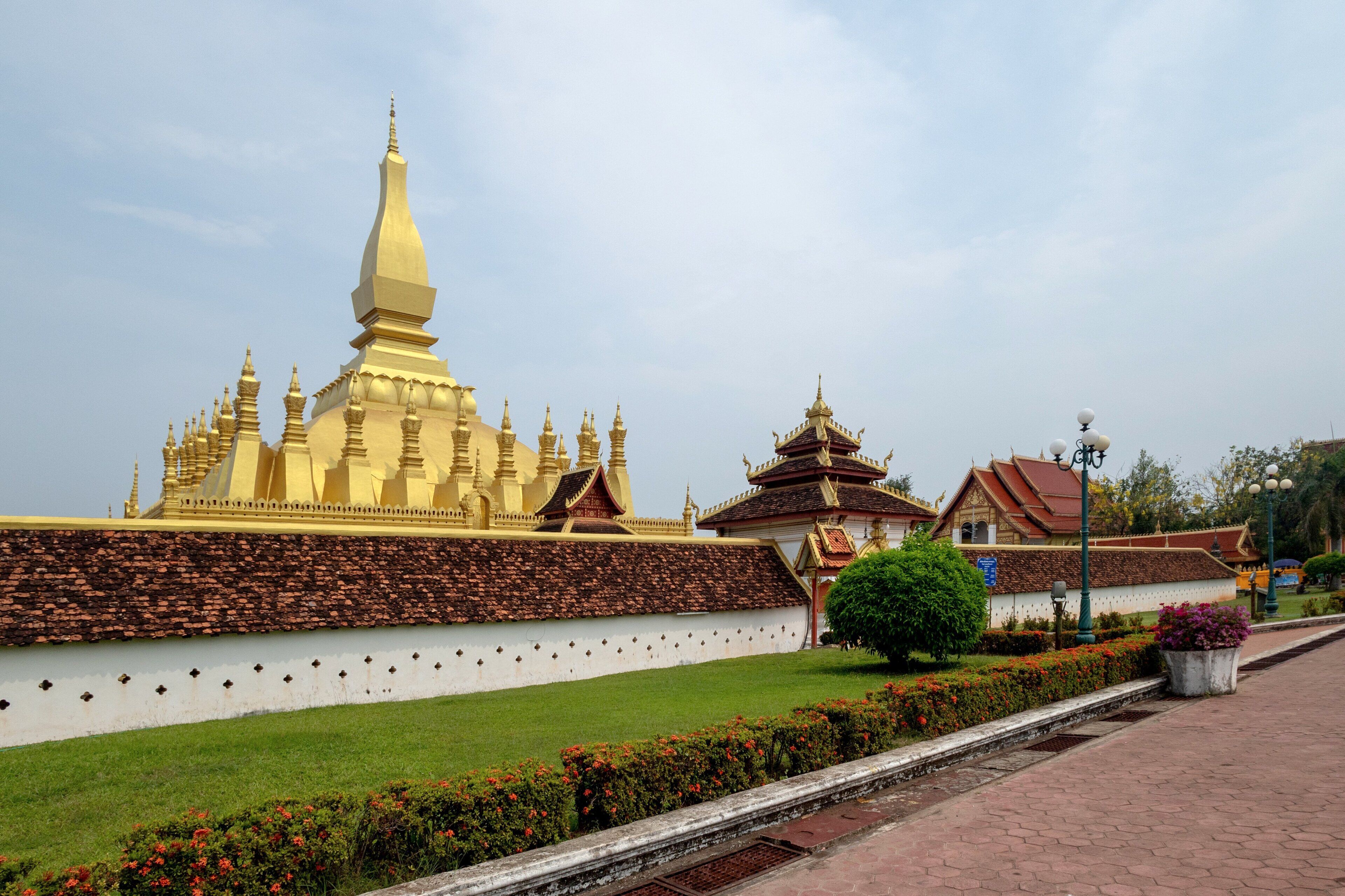 A large golden stupa with multiple tiers and a smaller adjacent structure with a red roof.