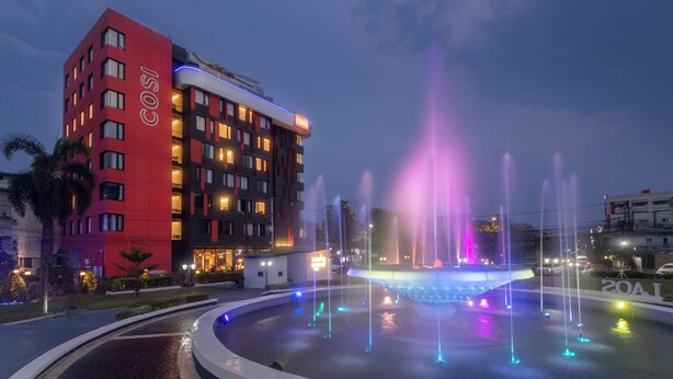 A hotel with a red facade and a fountain with colorful lights. - COSI Vientiane Nam Phu (Vientiane)