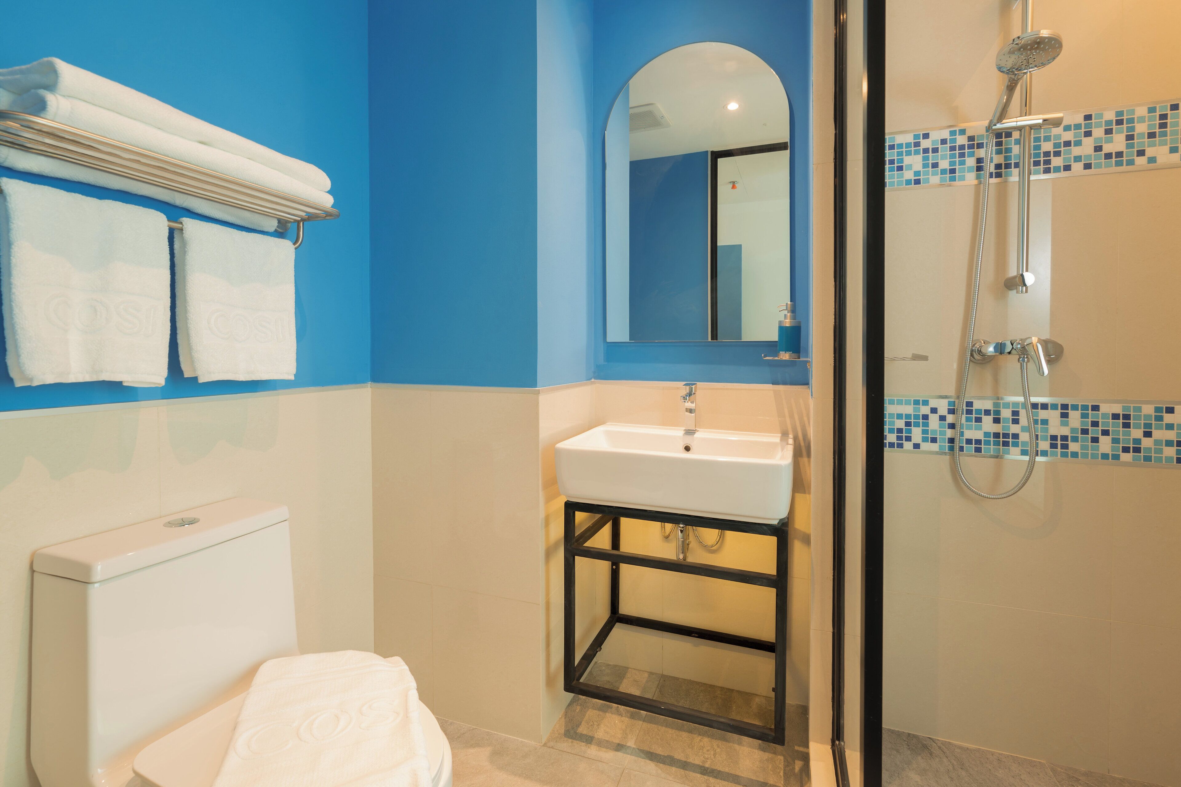 A bathroom with a white toilet, a sink with a mirror above it, and a shower area with a tiled wall.