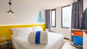 Een hotelkamer met een bed, een bureau, een stoel, een raam en een decoratie aan de muur.