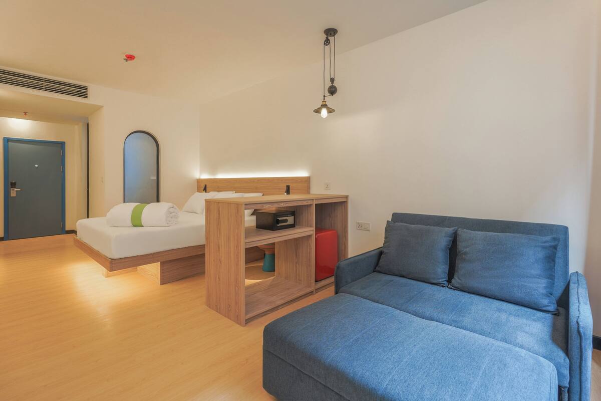 Een moderne kamer met een houten bed, een blauwe bank en een houten wandrek.