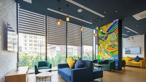 A modern hotel lobby with a blue sofa, green armchairs, and a colorful mural on the wall. - COSI Vientiane Nam Phu (Vientiane)