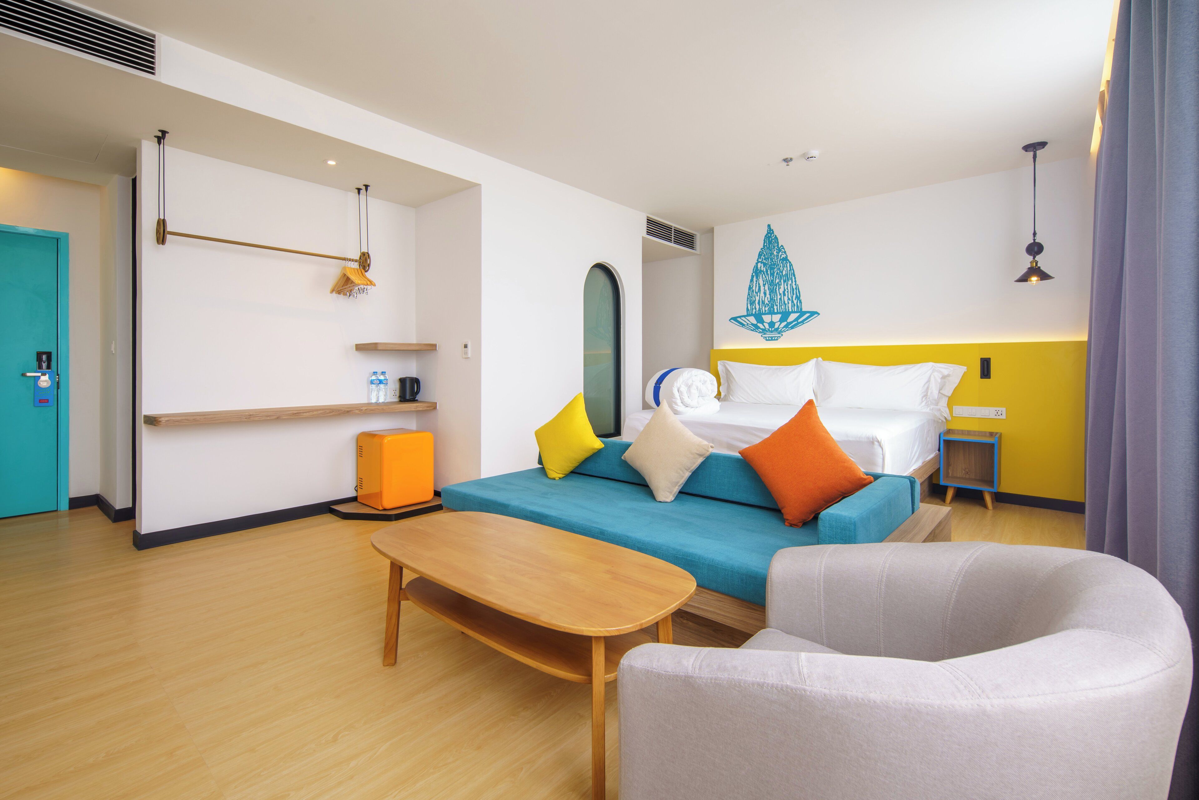 Een moderne hotelkamer met een bed, een bank, een houten tafel en een klein bijzettafeltje.