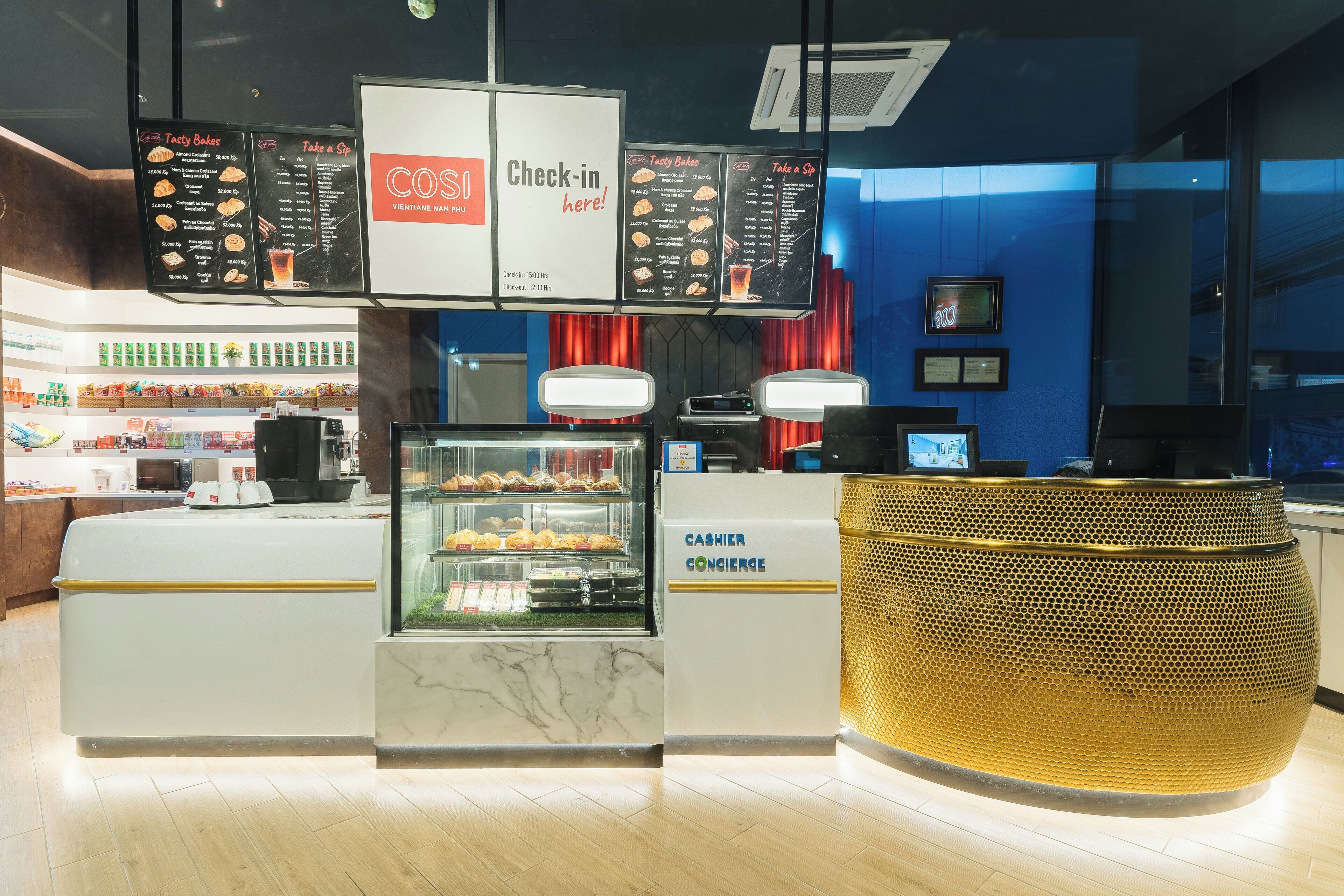 Ein modernes Café mit Check-in-Schalter, Speisekarten und einer Vitrine mit Backwaren.