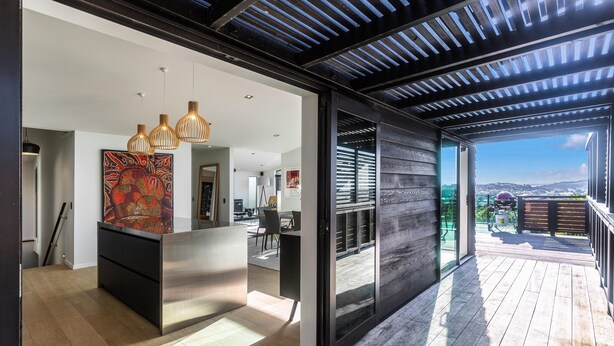 Una cocina moderna con una isla central, luces colgantes y un amplio ventanal con vistas a una terraza.