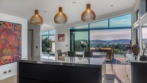 Una cocina moderna con una isla grande, luces colgantes y vistas a la ciudad.