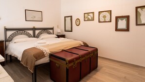 A neatly made bed with a brown blanket and a vintage suitcase on the floor. - Casa Mameli by Wonderful Italy (Conversano)