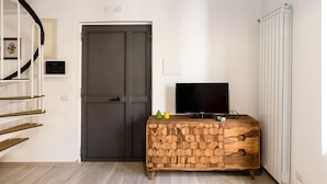 A room with a dark door, a wooden cabinet with a television, and a radiator. - Casa Mameli by Wonderful Italy (Conversano)