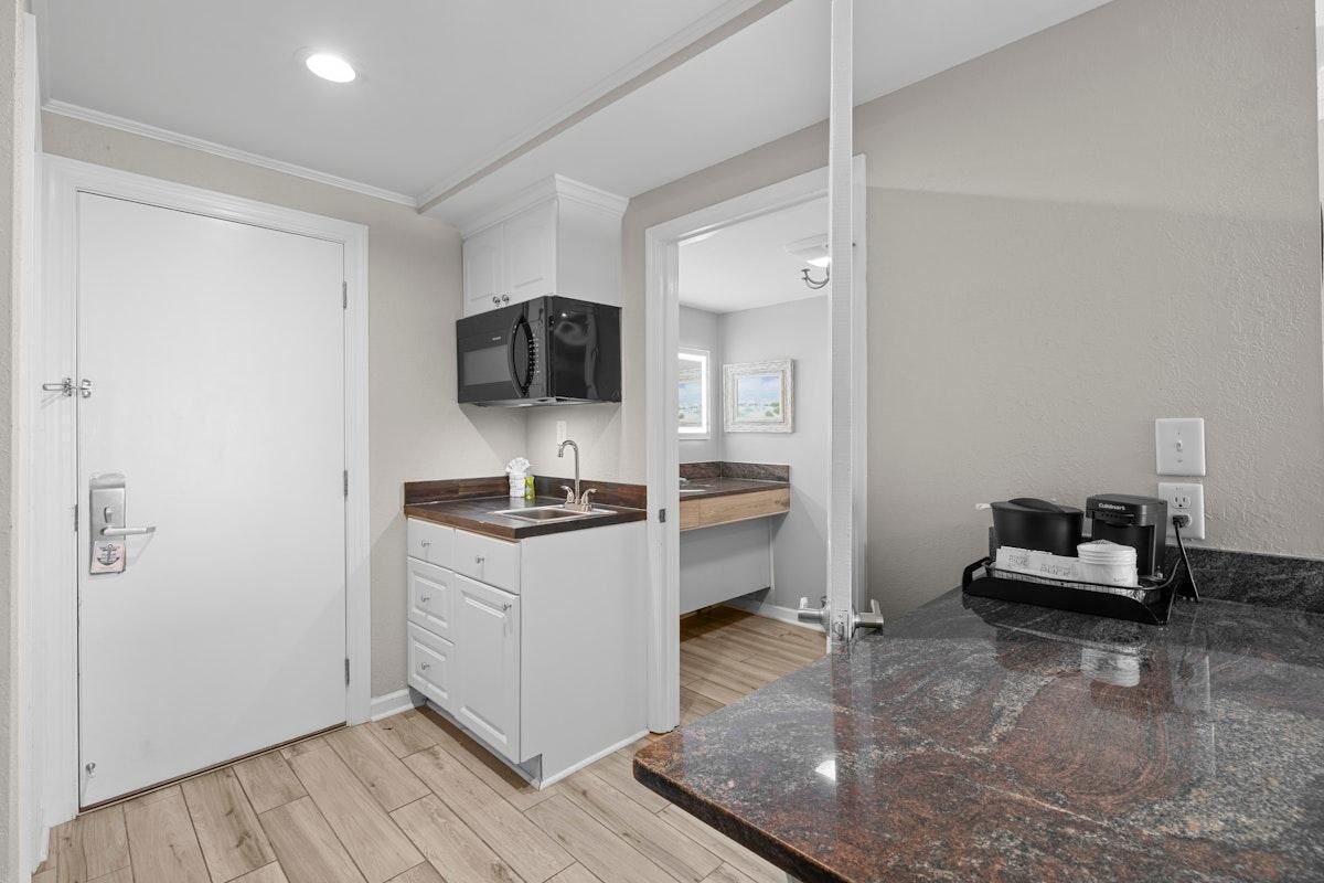 A compact kitchen with a microwave, sink, and coffee maker.