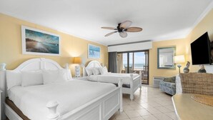 A hotel room with two beds, a ceiling fan, a TV, and a view of the sea. - Coastal Getaway in our Oceanfront Dune Room (Pawleys Island)