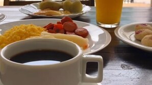 A table with breakfast items including eggs, sausages, and a glass of orange juice. - Pousada Brisa Suítes (Ipojuca)