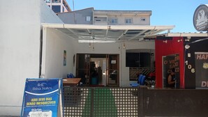 A hotel entrance with a covered outdoor seating area, a visible reception desk, and a sign advertising room rates. - Pousada Brisa Suítes (Ipojuca)