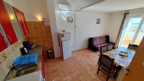 A compact kitchen with a refrigerator, stove, and sink. There's a dining area with a table and chairs.