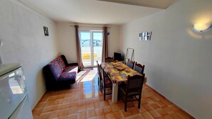 A compact living space with a dining area, a sofa, and a kitchenette.