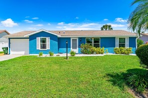 A single-story house with a blue exterior, a front garage, and a well-maintained lawn. - ⚓Sunset Getaways! Private Heated Pool home, Cinema/Arcade Room⚓ (Bradenton)