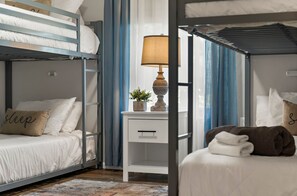 A bunk bed room with a bedside table, lamp, and a small potted plant.