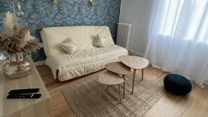 Een woonkamer met een bank, een salontafel, een vloerkleed en een decoratieve vaas.