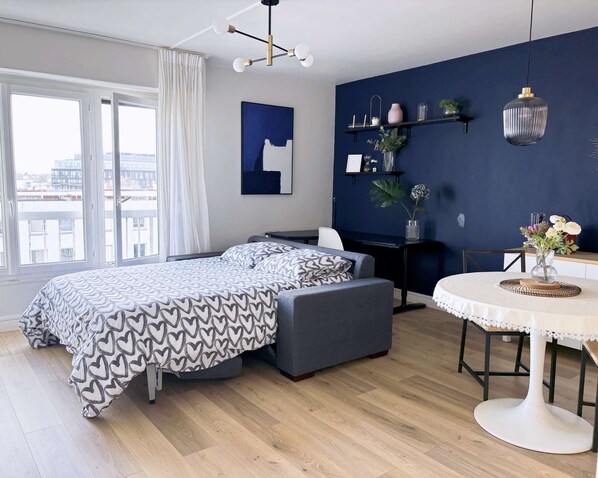 A modern bedroom with a bed, a desk, a chair, and a dining table.
