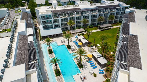 A modern hotel with a rooftop pool, multiple balconies, and a well-maintained garden area.