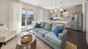 A modern living room with a grey sofa, a coffee table, and a balcony with a view of the city.