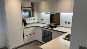 Una cocina moderna con armarios blancos, una estufa negra y un lavavajillas empotrado.