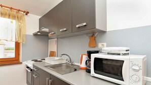 A compact kitchen with a stove, sink, and microwave. - Holiday apartment with air conditioning (Pula)