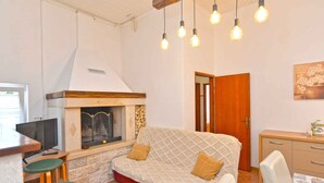 A cozy living area with a sofa, a fireplace, a television, and a dining table. - Holiday apartment with air conditioning (Rovinj)