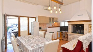 A spacious living area with a dining table, chairs, a red sofa, a kitchen area, and a fireplace. - Holiday apartment with air conditioning (Rovinj)