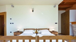 A bedroom with a wooden bed, two bedside tables, and a wall-mounted light fixture.