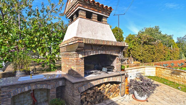 A brick outdoor kitchen with a chimney, a sink, and a potted plant.