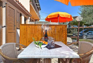 Enjoy al fresco dining in this patio area with a table for two, surrounded by a wooden fence and shaded by an umbrella.